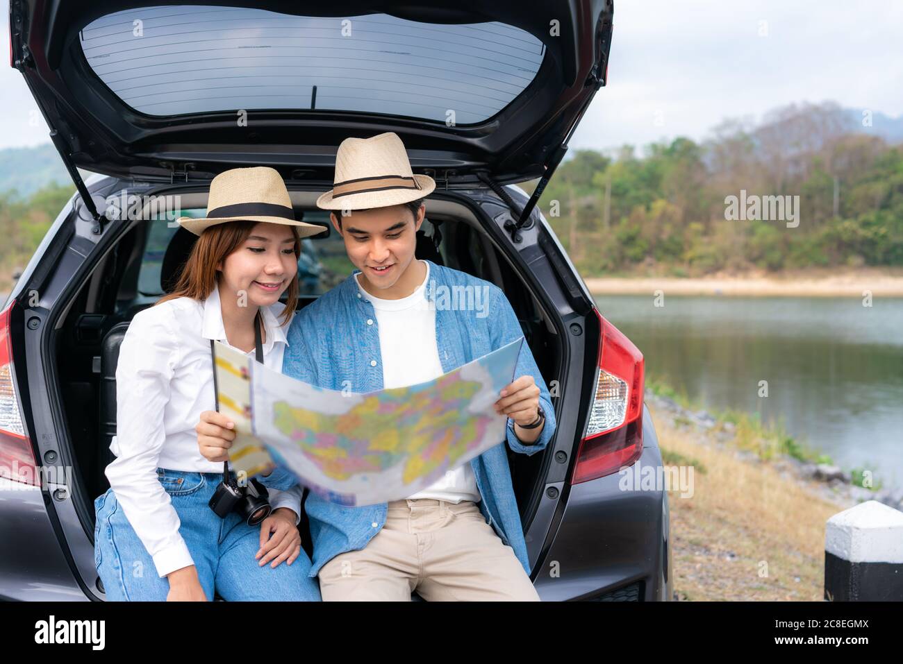 Portrait von asiatischen Paar sitzen im Auto und halten Karten auf der Suche nach dem nächsten Ziel für Reisen während Urlaub zusammen im Urlaub. Frohe romantische ti Stockfoto