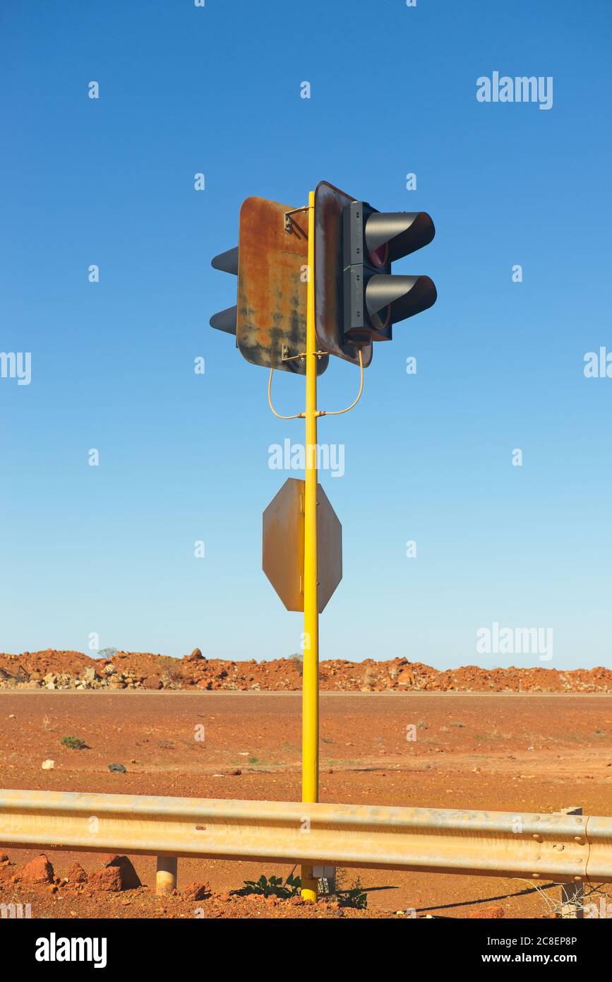 Ampel außer Betrieb auf gelbem Pol am abgelegenen Outback Highway in Australien, mit rotem Boden und sonnigem blauen Himmel als Hintergrund und Kopierraum. Stockfoto