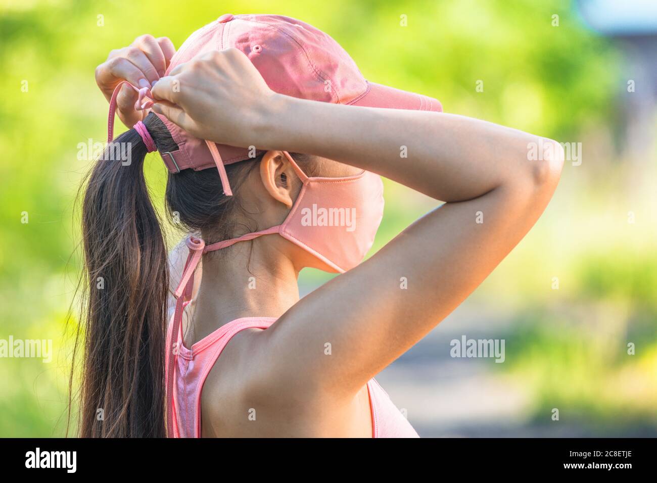 COVID-19 Maske Frau trägt Coronavirus Schutz binden String Krawatten Tuch Maske draußen im Outdoor Sommerpark Stockfoto