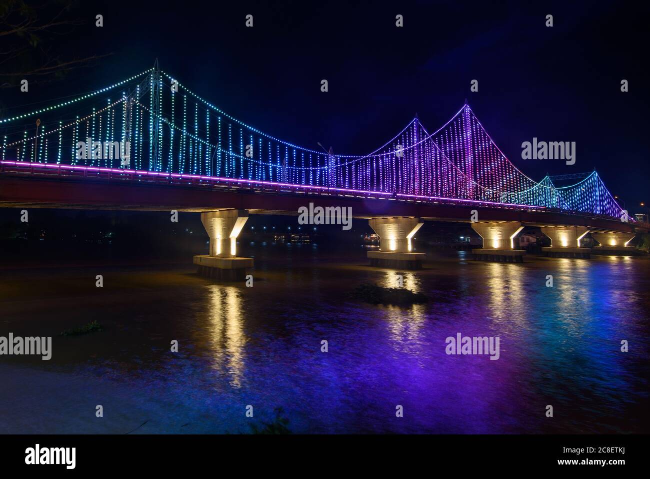 Die Landschaft der TAPI Flussbrücke mit der bunten Lichtdekoration bei Dämmerung in der Surat Thani Provinz, Thailand. Stockfoto