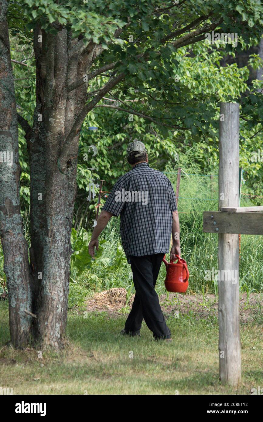 Mann, der mit einem Gartenbewässerungsbehälter läuft Stockfoto