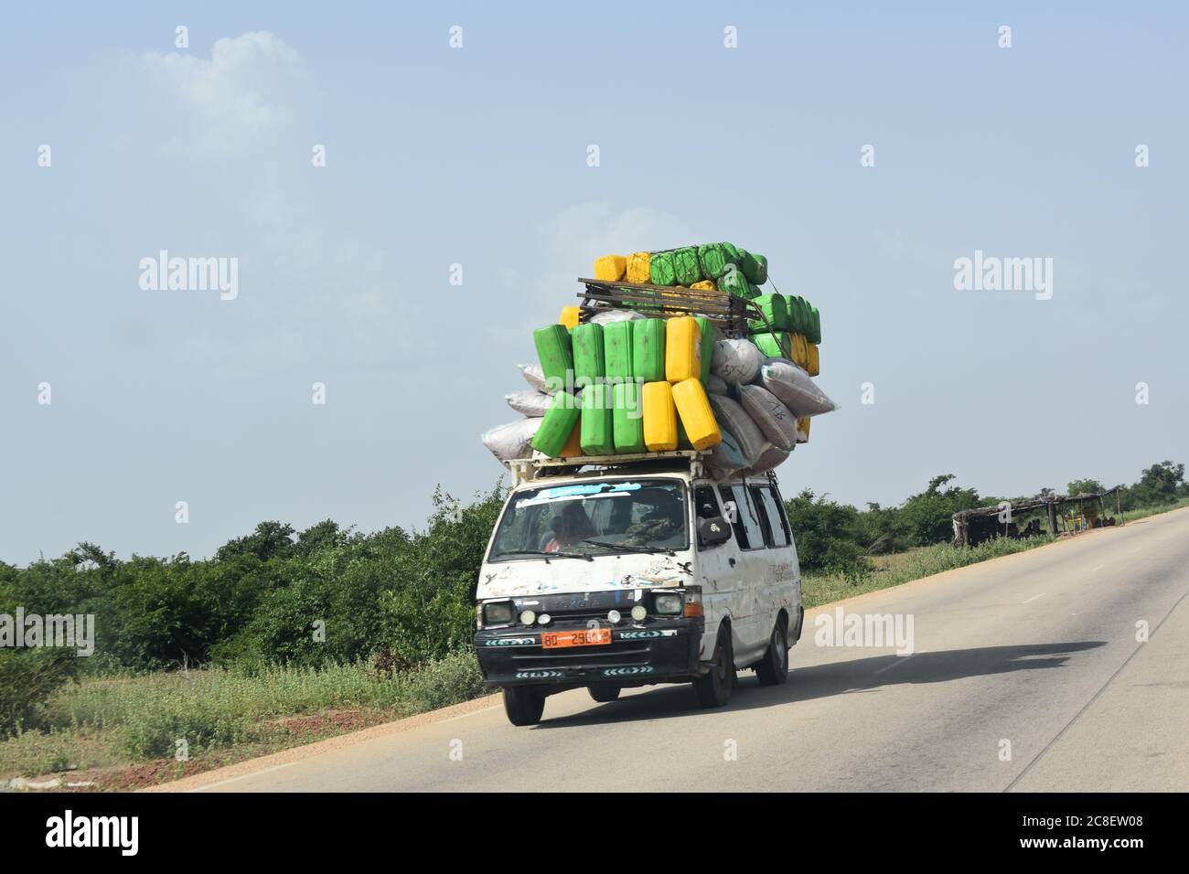 Ein überladener Passagiertransporter, der mit Gepäck überhäuft ist, fährt auf einer Autobahn im ländlichen Niger, Afrika Stockfoto