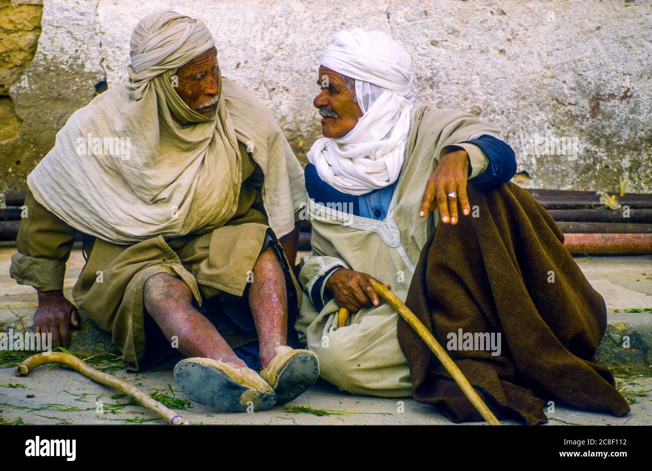 Zwei ältere Männer unterhalten sich in einer ruhigen Straße in Douz, Tunesien, einer Dattenanbau-Oasenstadt am Rande der Sahara Stockfoto