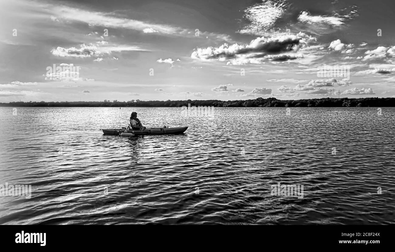 Tourist auf einem Kajak spät am Nachmittag auf einem ruhigen See in schwarz und weiß. Stockfoto