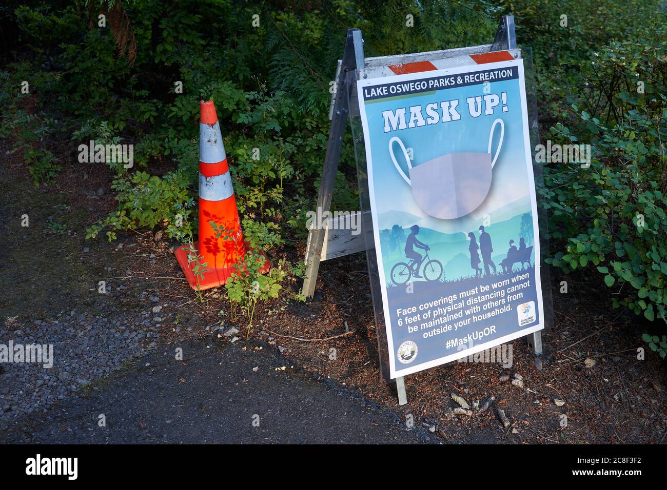 Die Beschilderung für die Politik der Außenmaske ist auf einem Wanderweg in einem Lake Oswego Stadtpark zu sehen. Oregon erweitert seine landesweite Gesichtsmaske Politik als COVID-19 Fälle Anstieg. Stockfoto