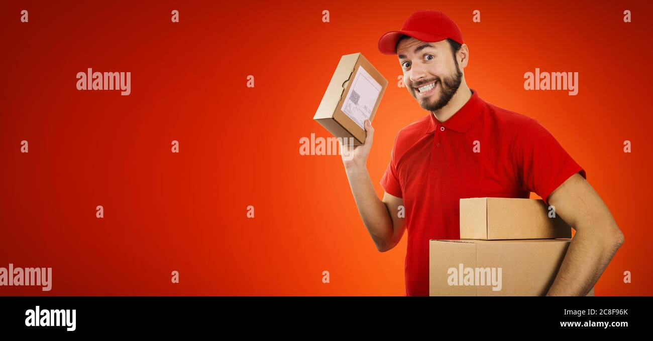 Lustige Lieferdienst Mann mit Box in der Hand auf rotem Hintergrund mit Kopierraum Stockfoto