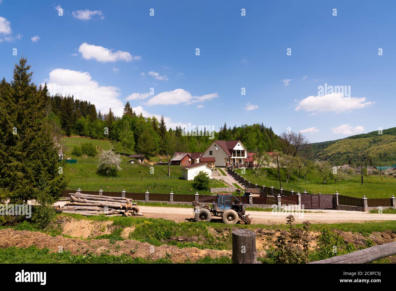 Neues Einfamilienhaus in den Bergen, Traktor auf der Straße Stockfoto
