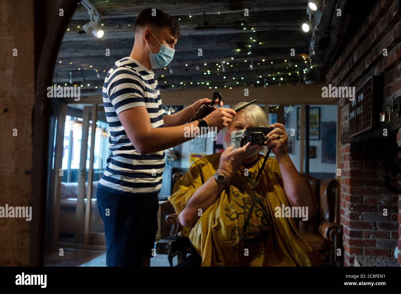 Thaxted, Großbritannien. Juli 2020. Thaxted Essex UK obligatorisches Tragen von Gesichtsmasken beim Haarschnitt 24. Juli 2020 im Friseursalon und Friseursalon von ‘Pfdles and Jellyspoons in Thaxted schneidet Jordan den Fotografen zum ersten Mal seit mehr als vier Monaten die Haare, weil das Coronavirus gesperrt wurde. Ab heute sind in England alle Kunden und Mitarbeiter in Friseuren, Cafés, Bars, Geschäften und Restaurants gesetzlich verpflichtet, Gesichtsmasken zu tragen oder eine Geldstrafe von £100 zu riskieren. Der Fotograf ist Model freigegeben. Foto: BRIAN HARRIS/Alamy Live News Stockfoto