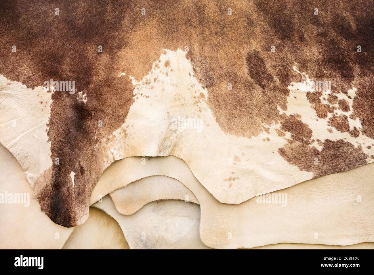 Haufen von verschiedenen braunen mit weißen Rindshäuten Stockfoto