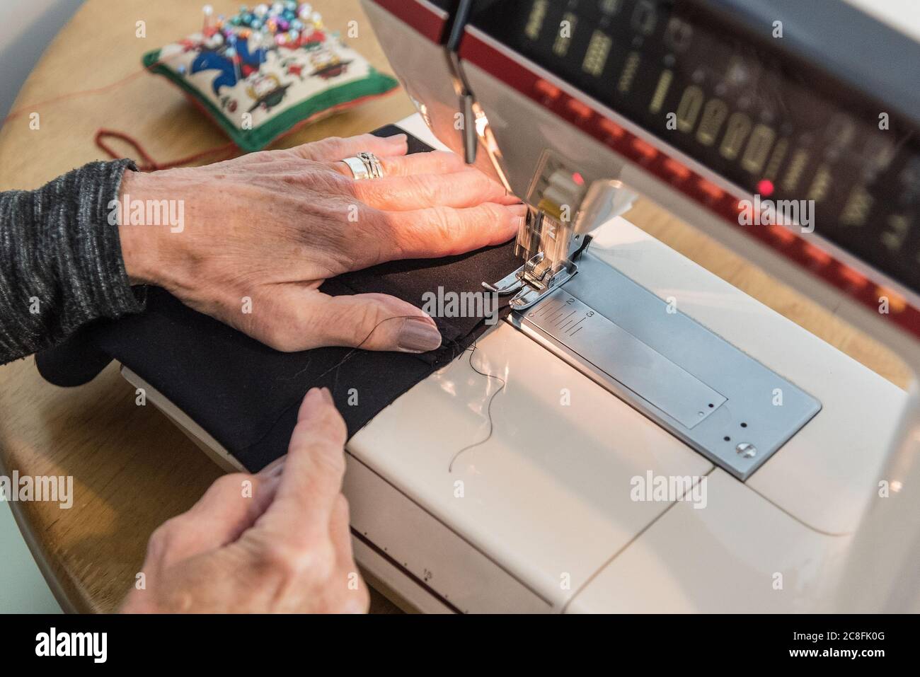 Eine Frau, die eine Nähmaschine zum Nähen von Material benutzt. Stockfoto