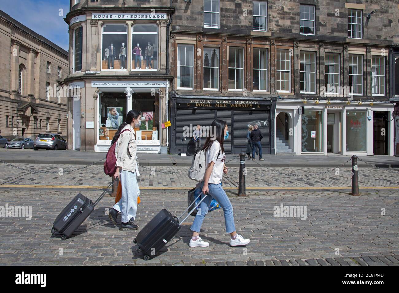 Stadtzentrum, Edinburgh Schottland, Großbritannien. 24. Juli 2020. Touristen scheinen nach 4 Monaten der Sperre wieder in die Straßen des Stadtzentrums zu tröpfeln und die Royal Mile mit Koffern und Gepäck in der Morgensonne zu Fuß zu gehen. Stockfoto