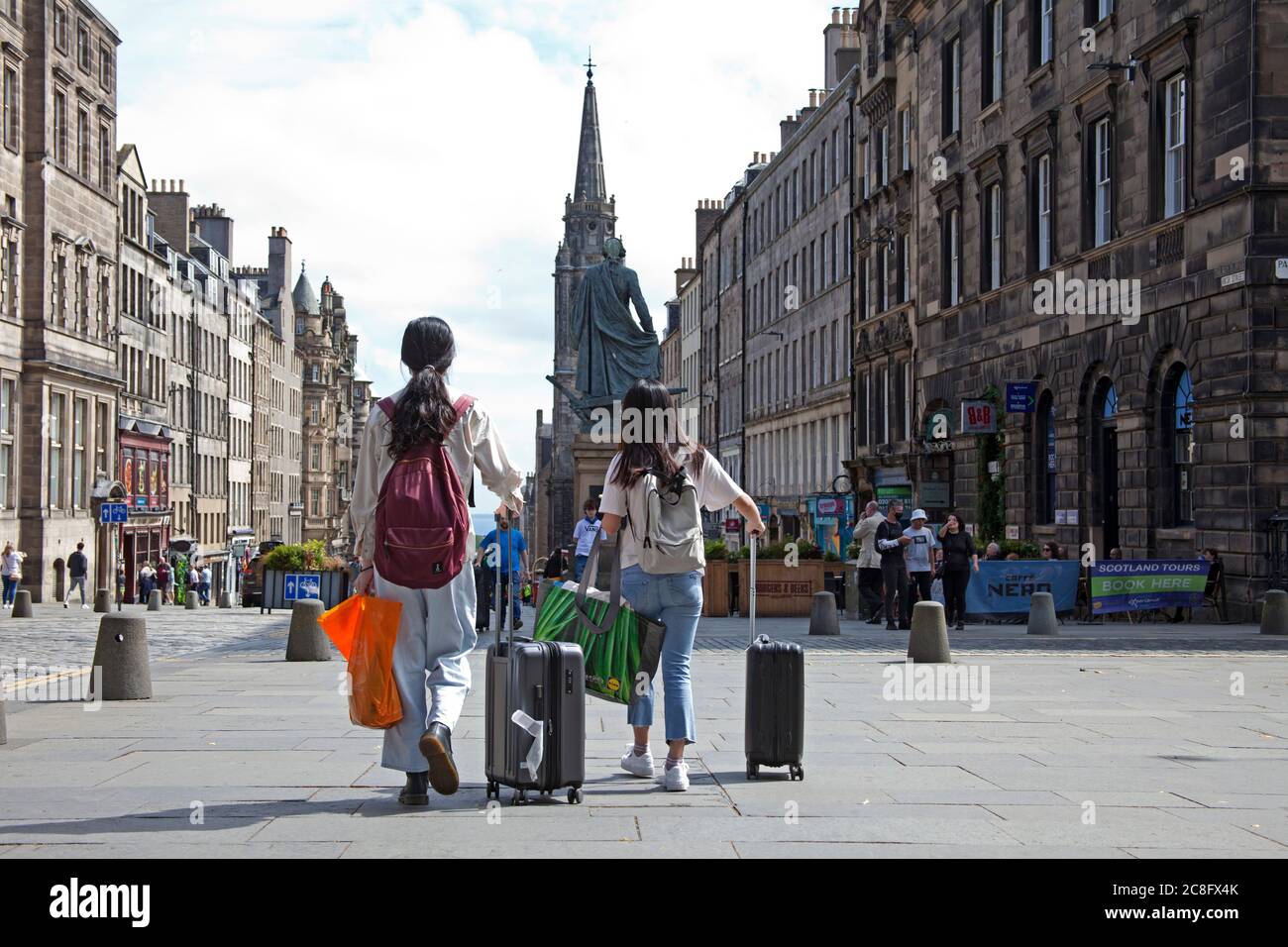 Stadtzentrum, Edinburgh Schottland, Großbritannien. 24. Juli 2020. Touristen scheinen nach 4 Monaten der Sperre wieder in die Straßen des Stadtzentrums zu tröpfeln und die Royal Mile mit Koffern und Gepäck in der Morgensonne zu Fuß zu gehen. Stockfoto