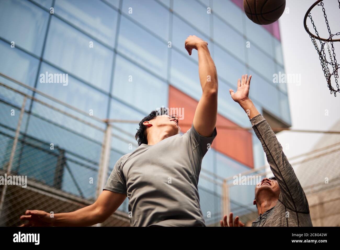 Zwei junge asiatische Männer spielen Basketball gehen für einen Rebound auf dem Outdoor-Platz Stockfoto