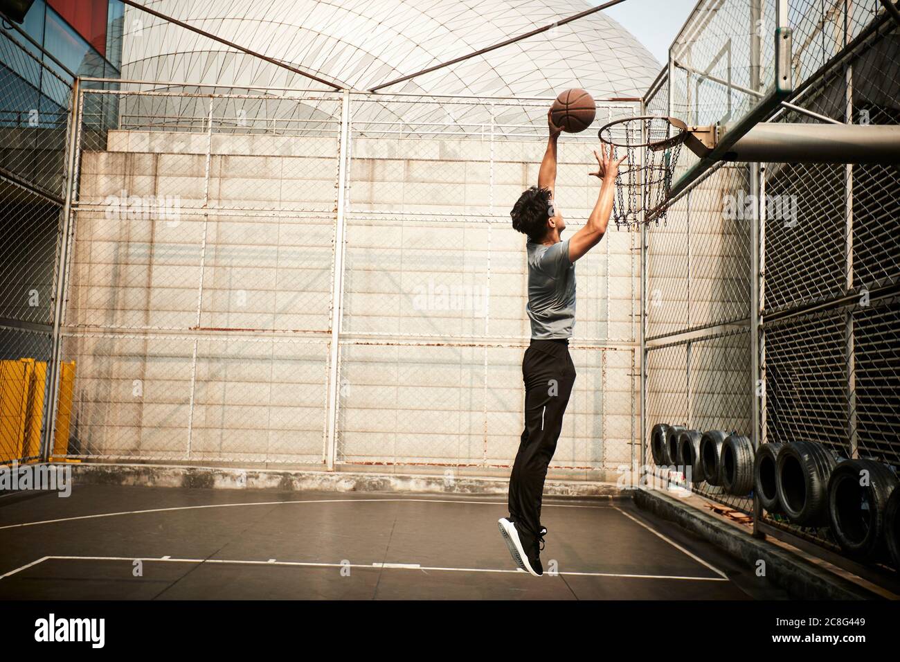 Junge asiatische Erwachsene Mann Basketballspieler versucht ein Dunk auf Outdoor-Platz Stockfoto