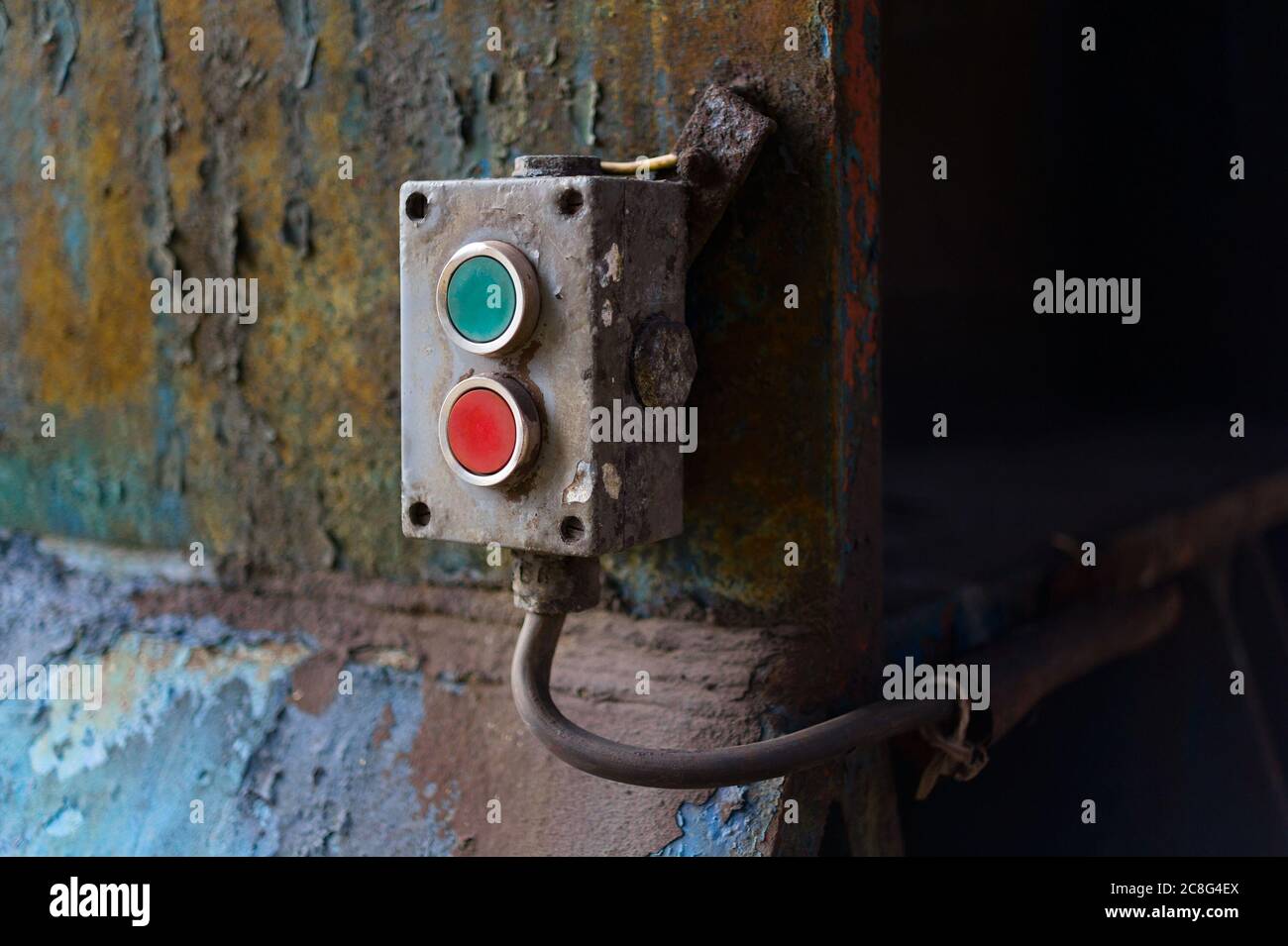 Gerät zur Steuerung von Industriemaschinen mit roter und grüner Taste zum ein- oder Ausschalten. Die verrostete Platte ist alt und verblasst Stockfoto