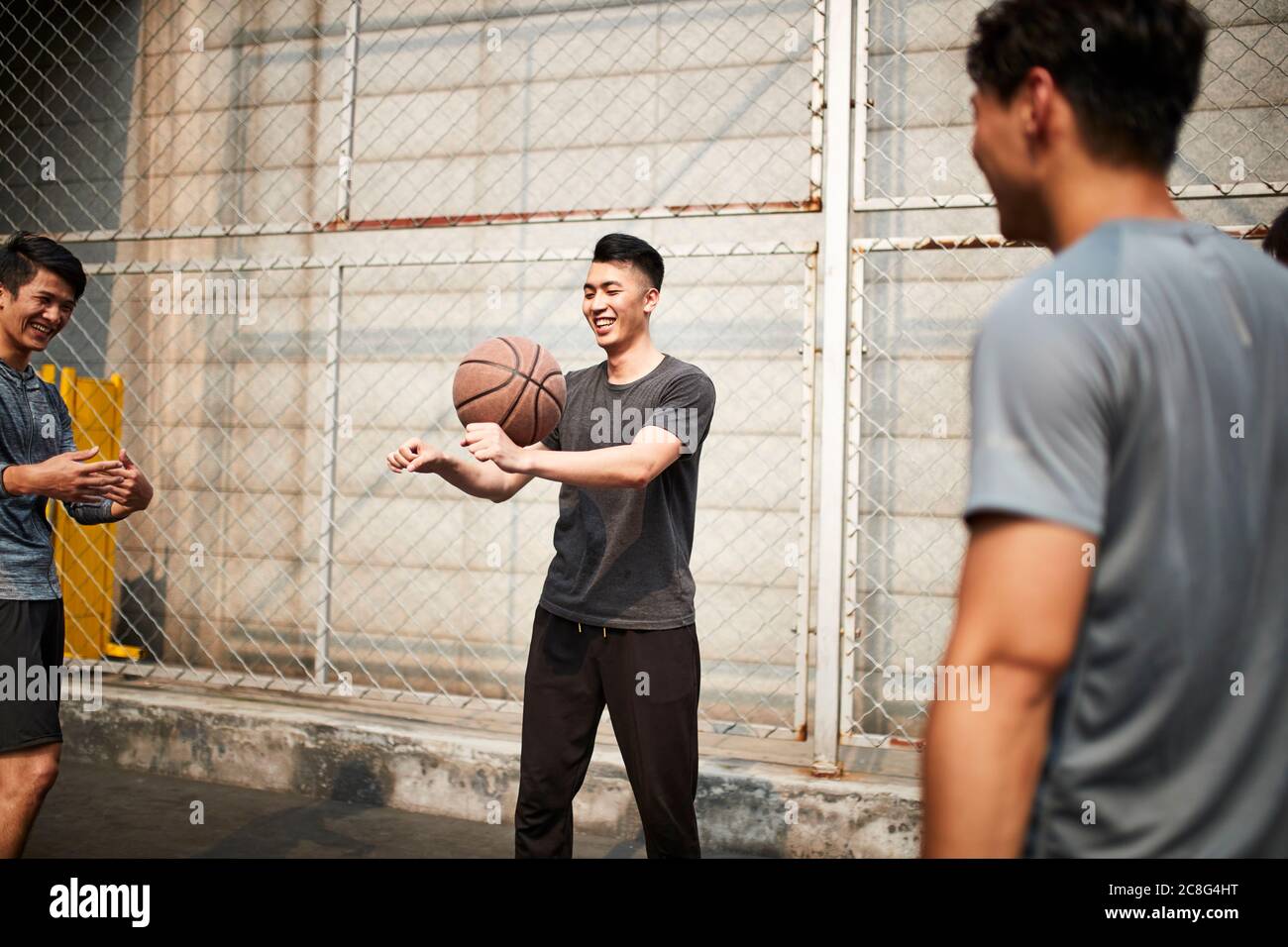 Junge asiatische Erwachsene Männer mit Spaß spielen mit Basketball im Freien Stockfoto