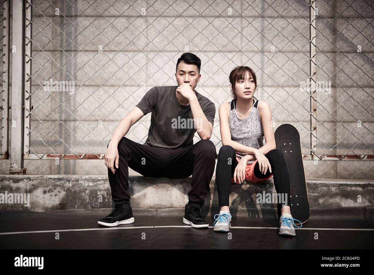 Junge asiatische Erwachsene Mann und Frau entspannen im Freien nach dem Training Stockfoto
