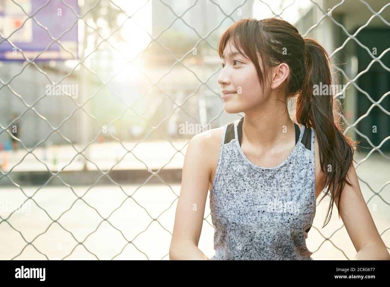 Outdoor-Porträt eines jungen asiatischen athletischen Mädchen weg lächelnd schauen Stockfoto