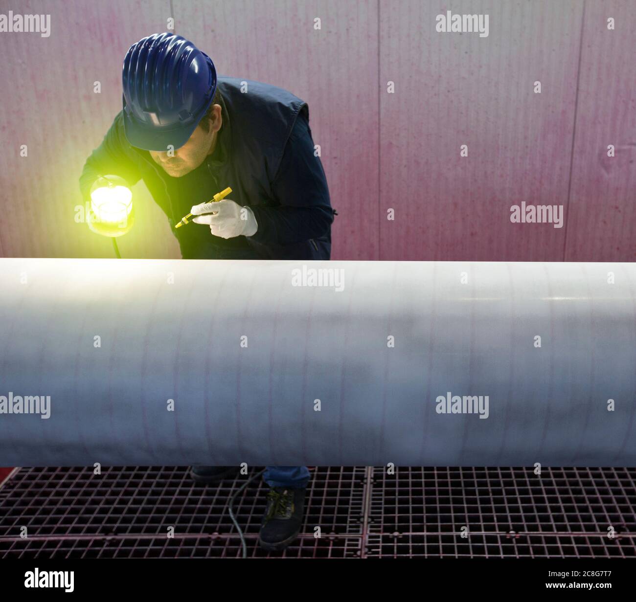 Mann, der in einer Stahlfabrik arbeitet und Stahlrohre inspiziert. Stockfoto