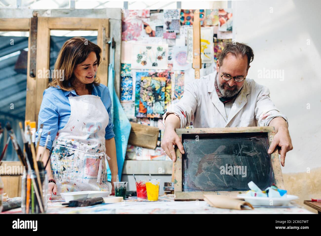 Frau, die gerade Mann Seide tun Siebdruck im Kreativstudio Stockfoto