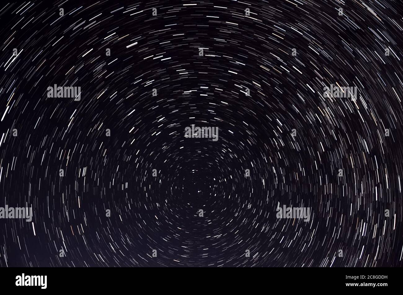 Abstrakter Raumhintergrund mit Spuren von Sternen, die sich um einen Polarstern in Form von kreisförmigen Bahnen vor dem Hintergrund des schwarzen Nachthimmels drehen Stockfoto