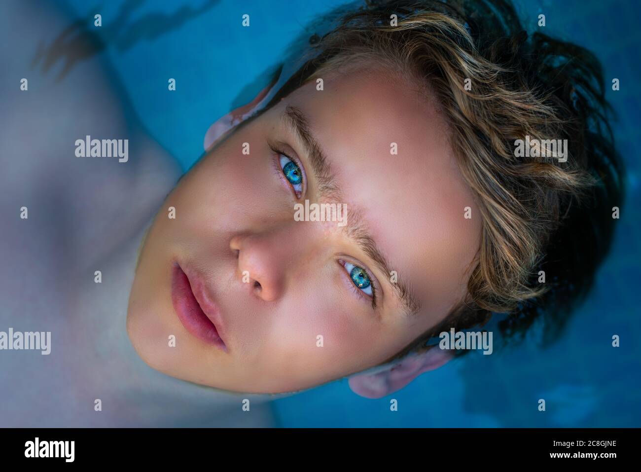 yong Mann mit erstaunlichen blauen Augen im Schwimmbad, genießen seinen Urlaub. Draufsicht Stockfoto