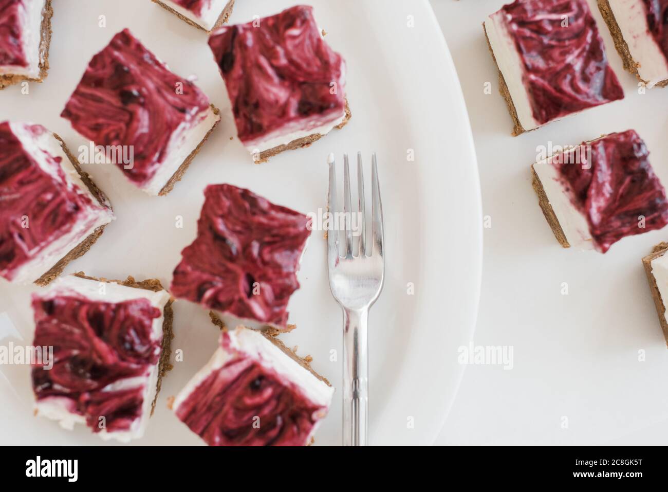 Erdbeerkäsekuchen in Quadrate auf einem Teller mit einem geschnitten Gabel Stockfoto Erdbeerkäsekuchen in Quadrate auf einem Teller mit einem geschnitten Gabel Stockfoto