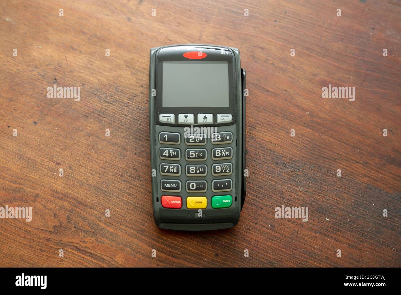 POS-Terminal isoliert auf Holzhintergrund, Draufsicht.Terminal-Kassenautomat für kontaktloses Bezahlen mit Kreditkarte. Bankausstattung, NFC. Stockfoto