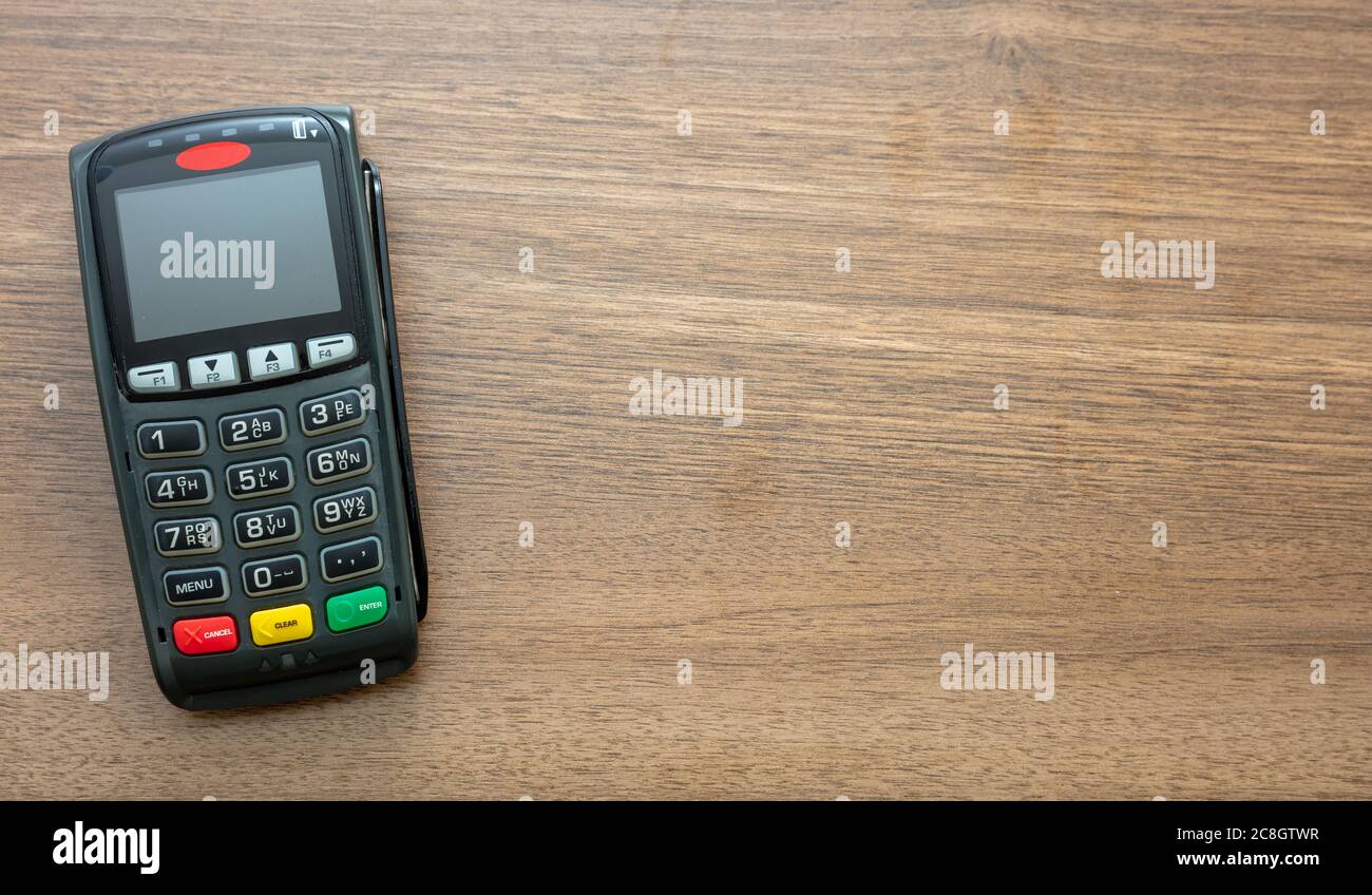 POS-Terminal isoliert auf Holzhintergrund, Draufsicht.Terminal-Kassenautomat für kontaktloses Bezahlen mit Kreditkarte. Bankausstattung, NFC. Stockfoto