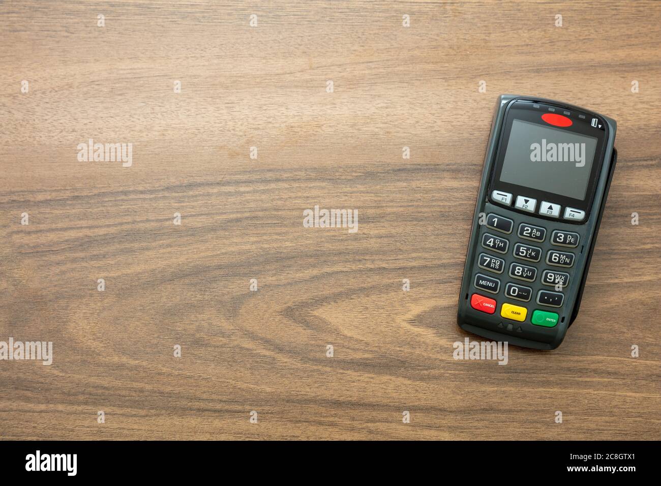 POS-Terminal isoliert auf Holzhintergrund, Draufsicht.Terminal-Kassenautomat für kontaktloses Bezahlen mit Kreditkarte. Bankausstattung, NFC. Stockfoto