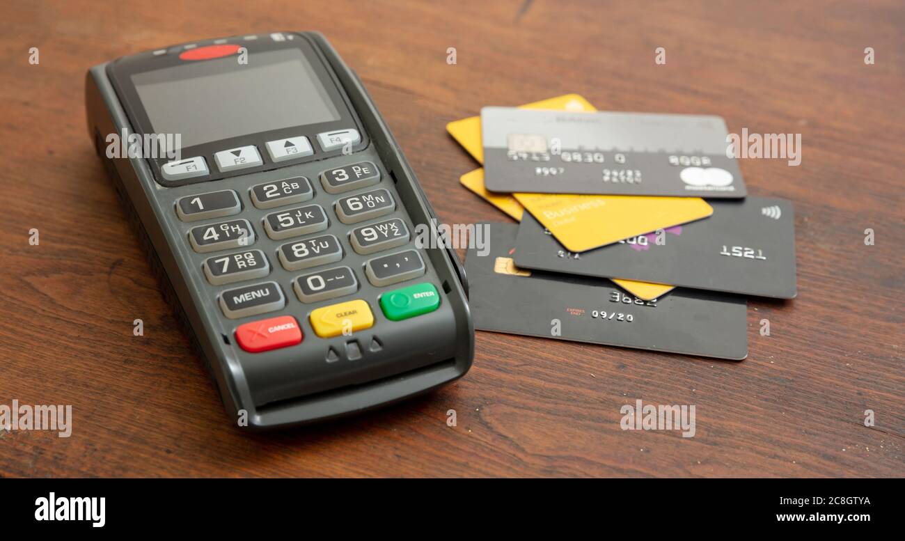 POS-Terminal und Kreditkarten auf Holzhintergrund, Terminal-Kassenautomat für kontaktloses Bezahlen. Bankausstattung, Konsumerismus, Shopping c Stockfoto
