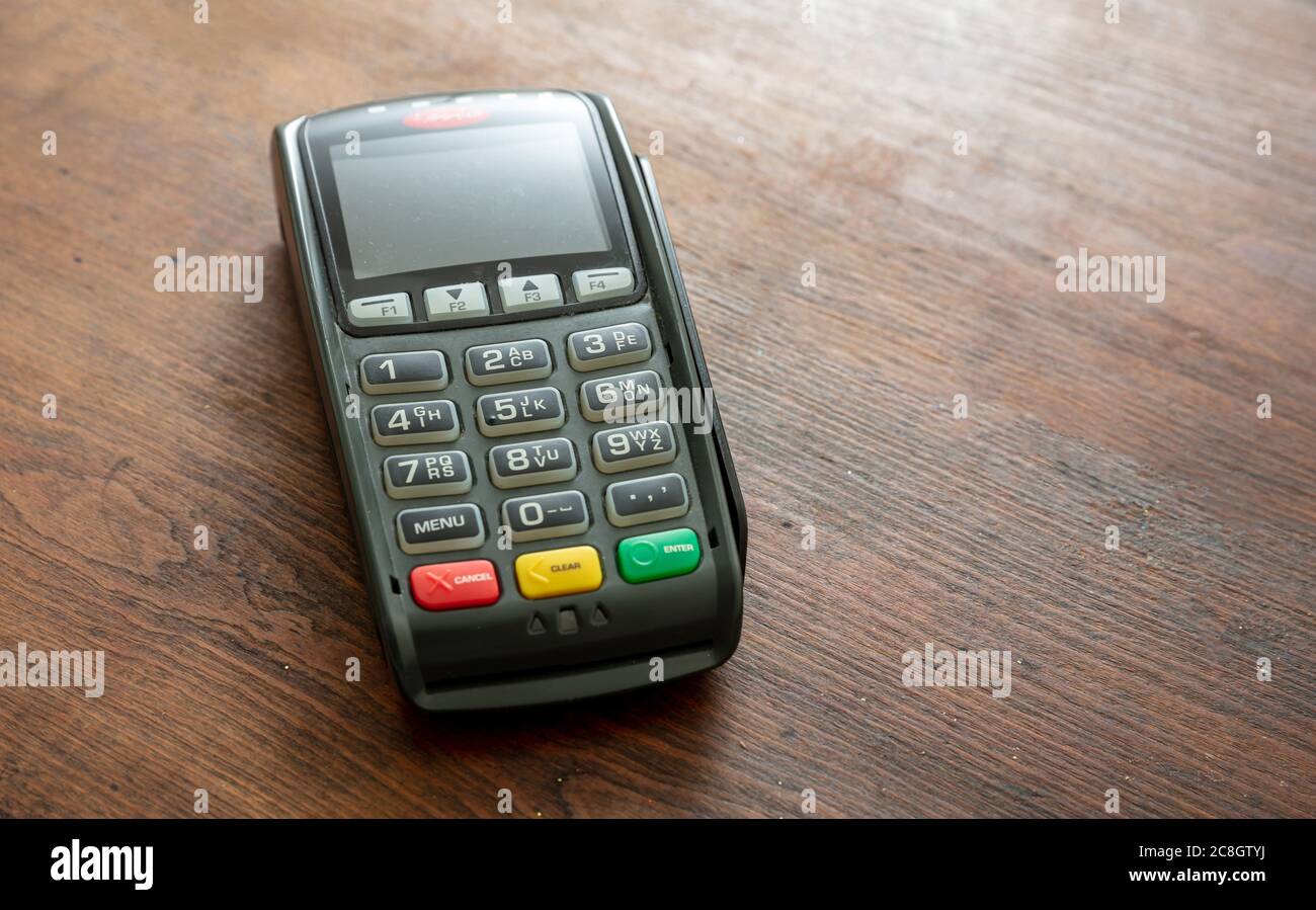POS-Terminal isoliert auf Holzhintergrund, Kopierraum.Terminal-Kassenautomat für kontaktloses Bezahlen mit Kreditkarte. Bankausstattung, NFC Stockfoto