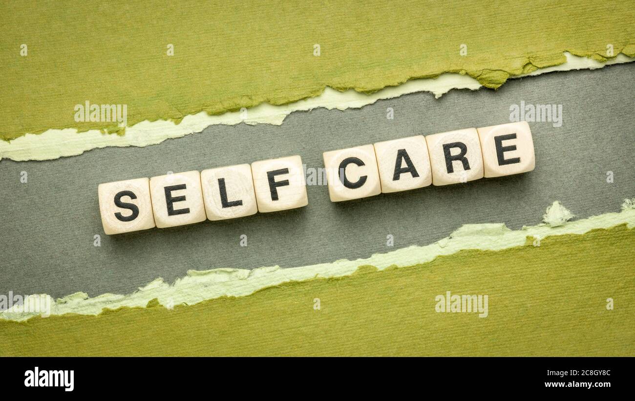 Self Care Wort abstrakt in Holzwürfelbuchstaben auf einem handgefertigten Papier - geistige, emotionale und körperliche Gesundheit Konzept Stockfoto