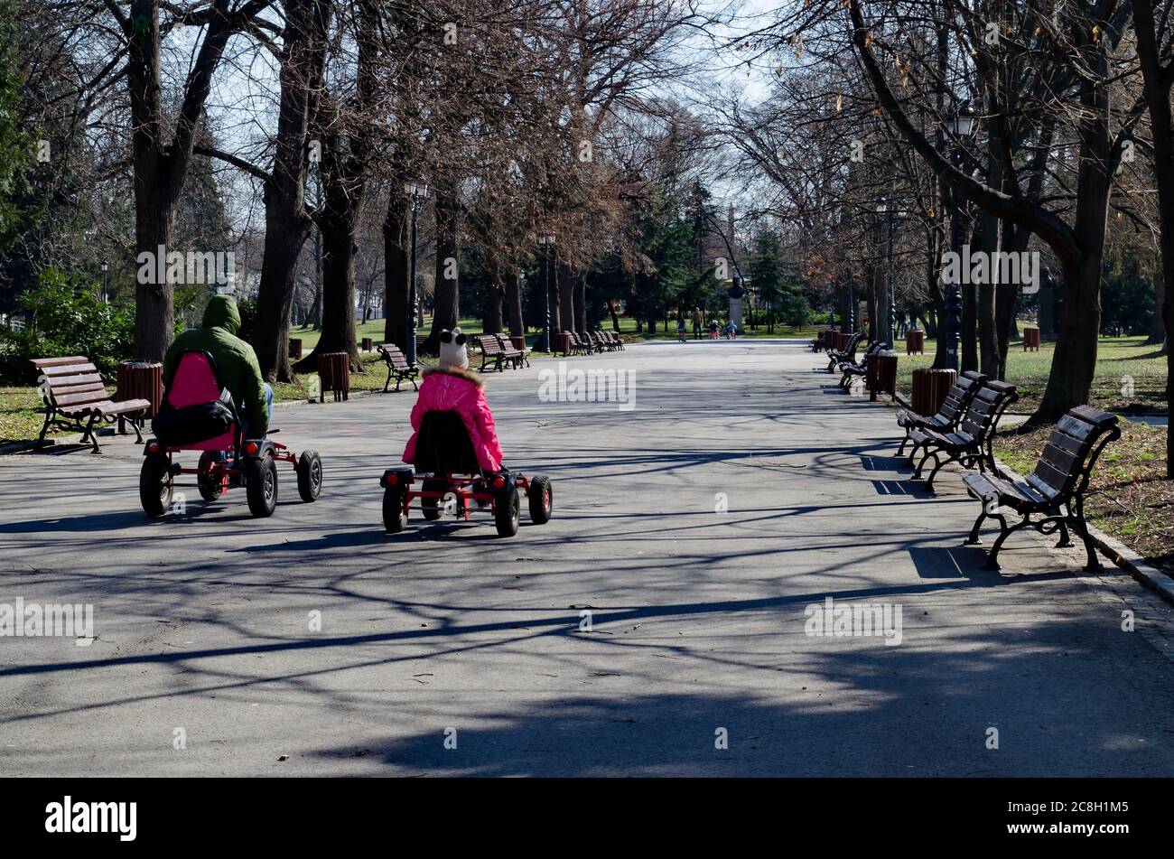 Frühlingshafte Ansicht von Lichtung, Wald, Holzbänken und ungeduldigen Besuchern im Park Sofia, Bulgarien Stockfoto