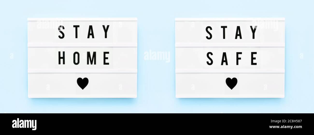 Banner. BLEIBEN SIE ZU HAUSE, BLEIBEN SIE SICHER in Leuchtkasten auf hellblauem Hintergrund geschrieben. Gesundheitswesen und medizinisches Konzept. Draufsicht. Quarantänekonzept. Stockfoto
