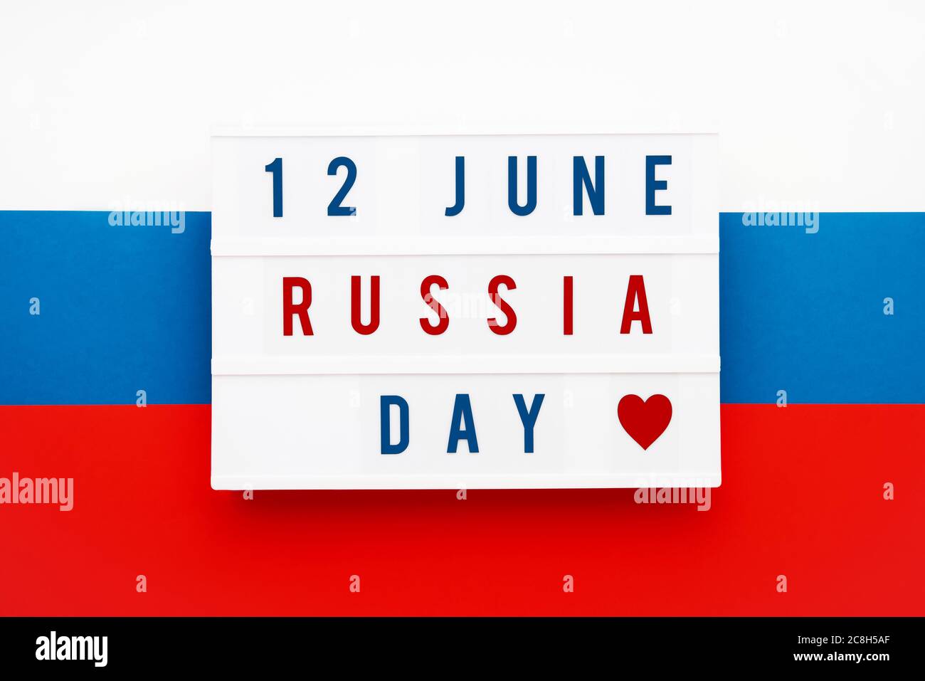 12 JUNI RUSSLAND TAG in Leuchtkasten auf russische Flagge Hintergrund geschrieben. Datum des Unabhängigkeitstages. Draufsicht. Stockfoto