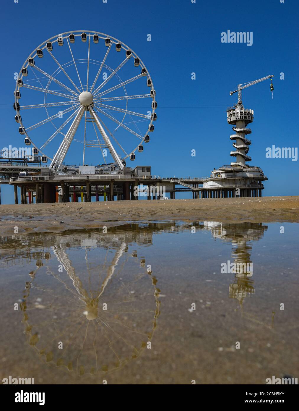 Der Bungee-Turm und das Rad auf Scheveningen Pier spiegelt sich in einem Teich am Strand Stockfoto