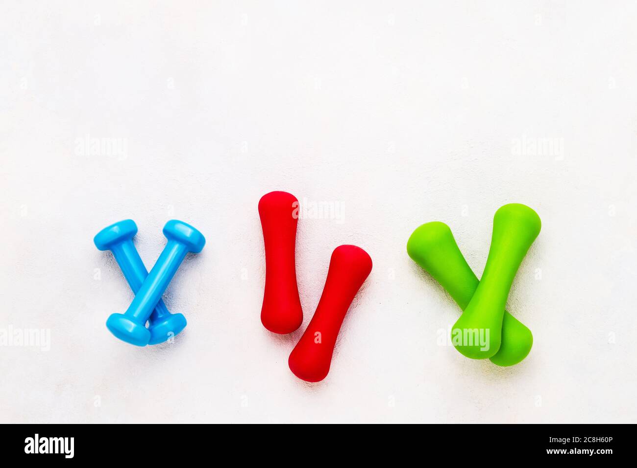 Bunte Kurzhanteln liegen auf betontem Hintergrund. Das Konzept des gesunden Lebensstils. Platz für Text kopieren, Draufsicht Stockfoto