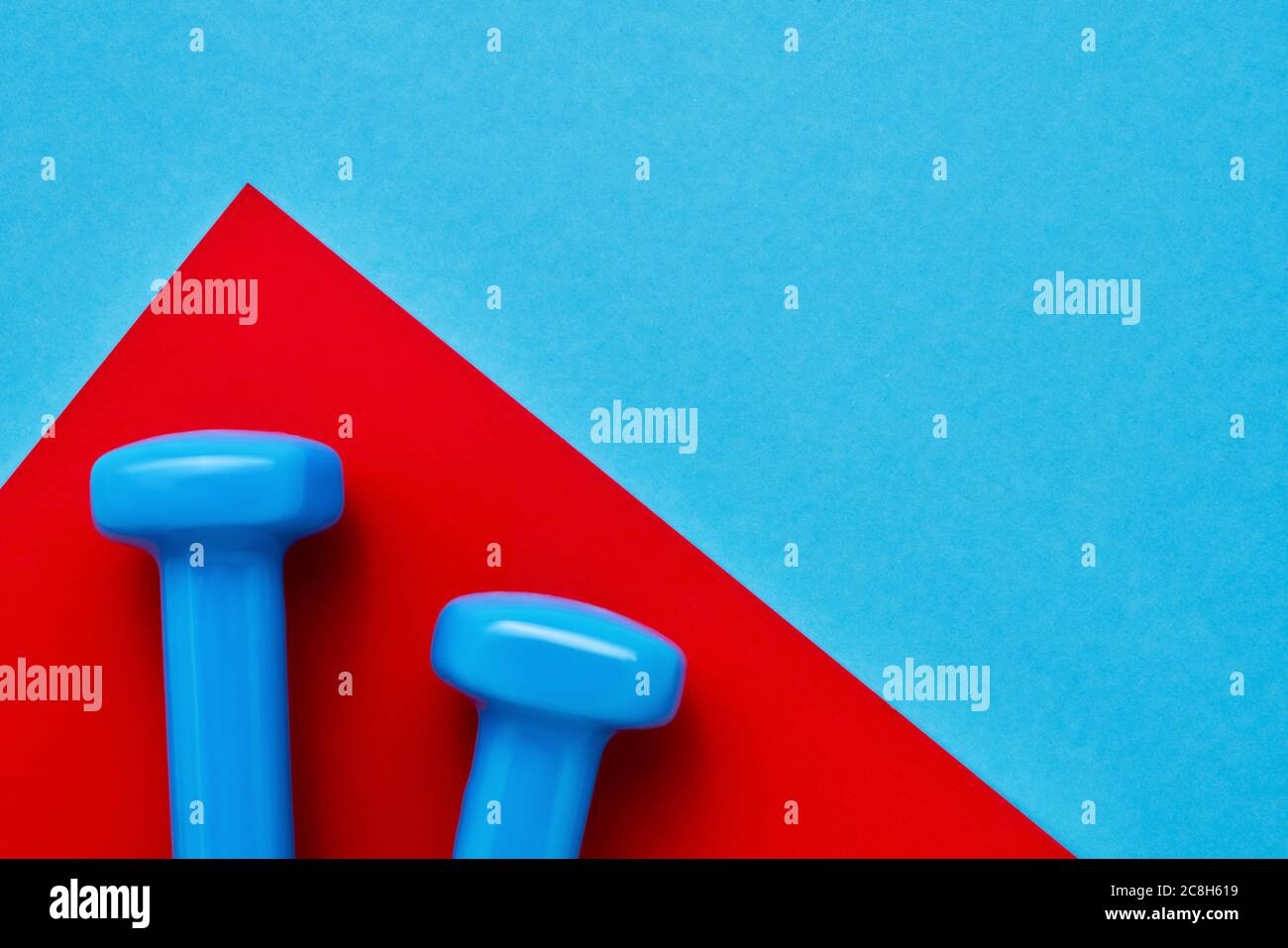 Blaue Kurzhanteln liegen auf rot-blauem Hintergrund. Das Konzept des gesunden Lebensstils. Platz für Text kopieren, Draufsicht Stockfoto