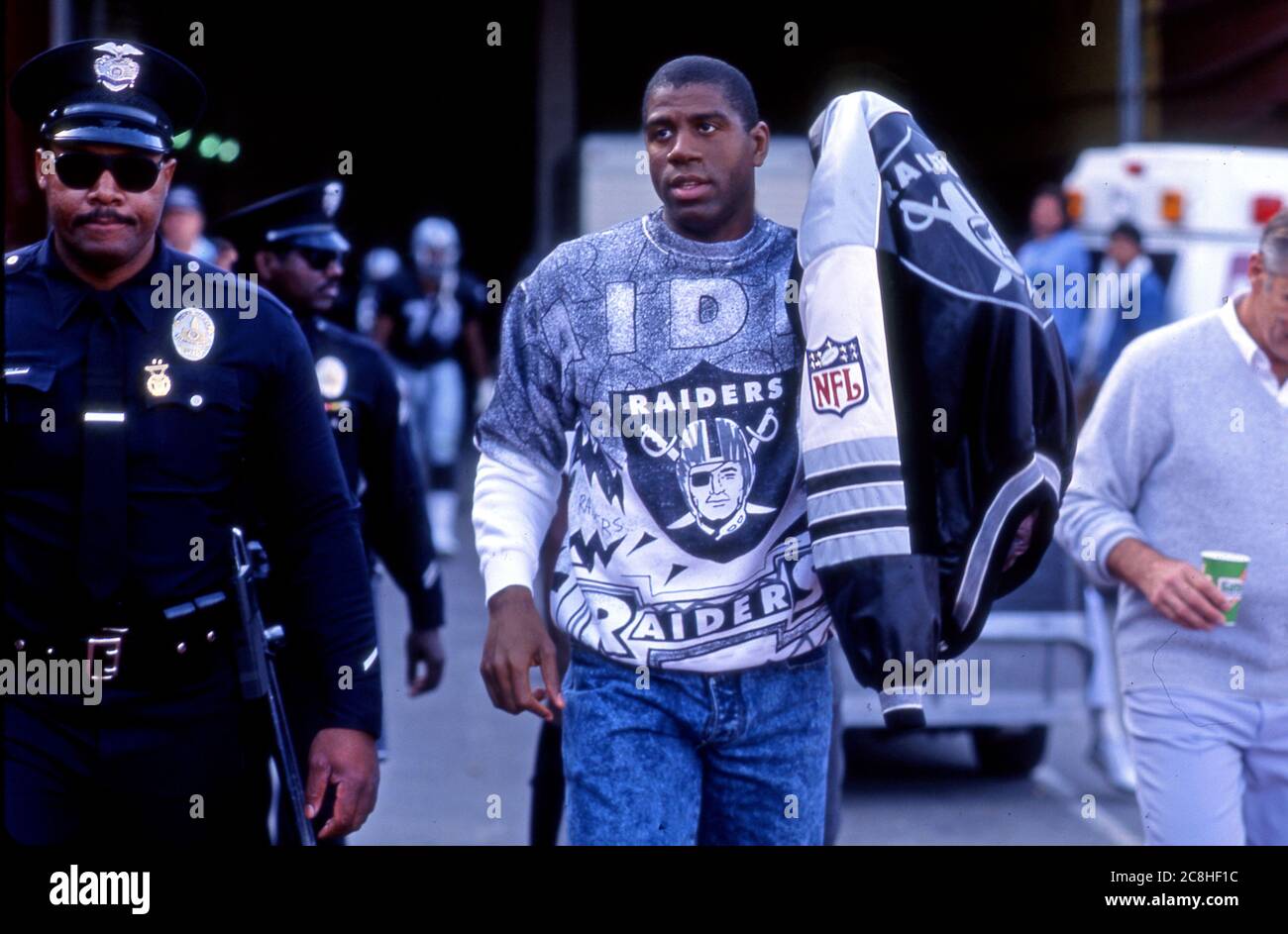 Magic Johnson of the Lakers Ankunft am Los Angeles Coliseum in Raiders Ausrüstung gekleidet, um einen L.A. zu beobachten Raiders NFL Fußballspiel im Jahr 1991. Stockfoto