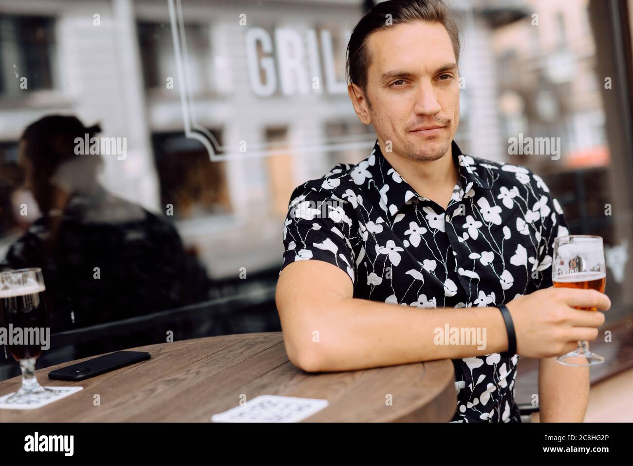 Glücklicher, attraktiver Mann, der sich entspannt und ein Bier in einem Pub trinkt. Stockfoto