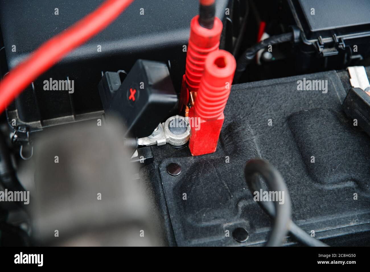 Aufspannung des Ladegeräts und der Startvorrichtung am Pluspol der Autobatterie in geringer Schärfentiefe Stockfoto