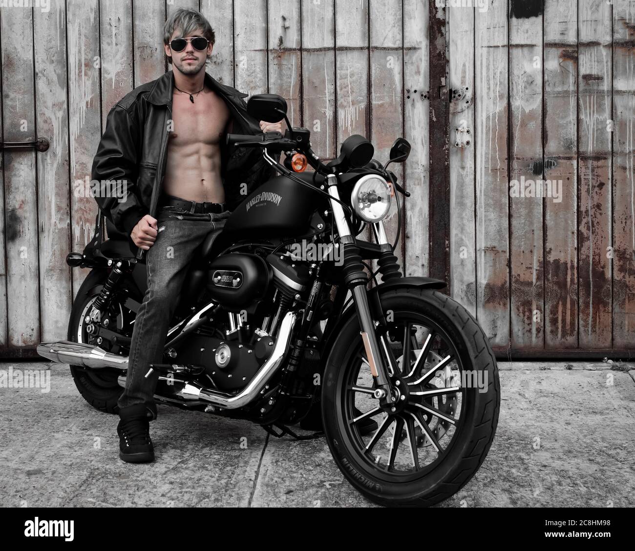 Panama City, Florida, USA 5/28/2014 Männliches Modell und Besitzer dieser Harley Davidson posiert vor alten rustikalen Lagerhäusern. Nur für redaktionelle Zwecke. Stockfoto