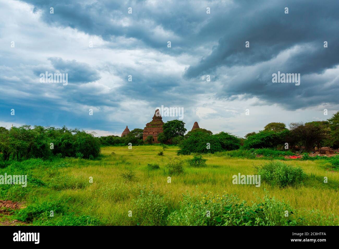 Eine große alte Pagode mit einem burmesischen Kunststil, die sich inmitten eines grünen Feldes im Weltkulturerbe von Myanmar befindet. Stockfoto