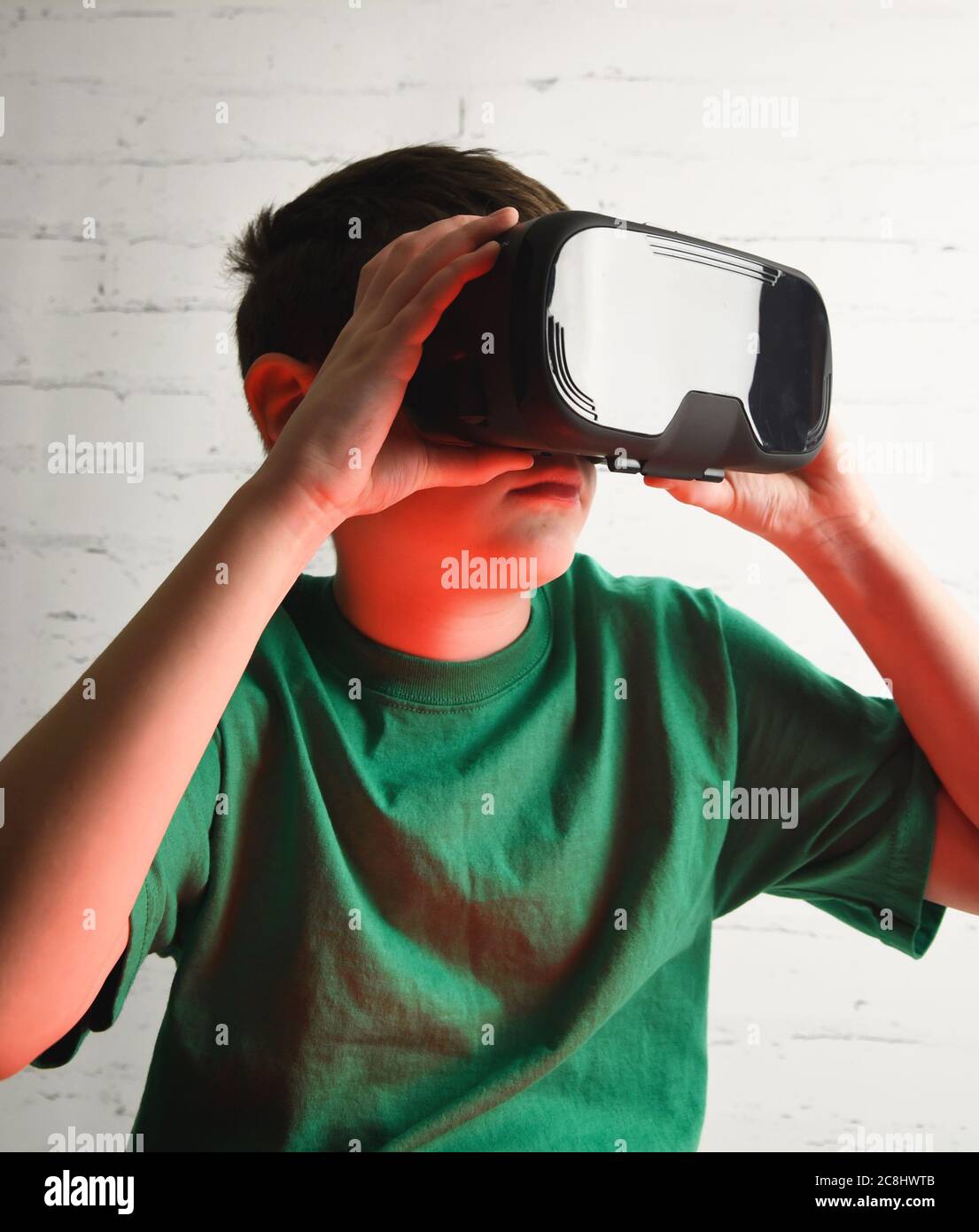 Ein Jugendlicher trägt eine virtuelle Relaity-Brille. Er hält das vr-Gerät in einem Raum für ein Tween-Future-Technologiekonzept. Stockfoto