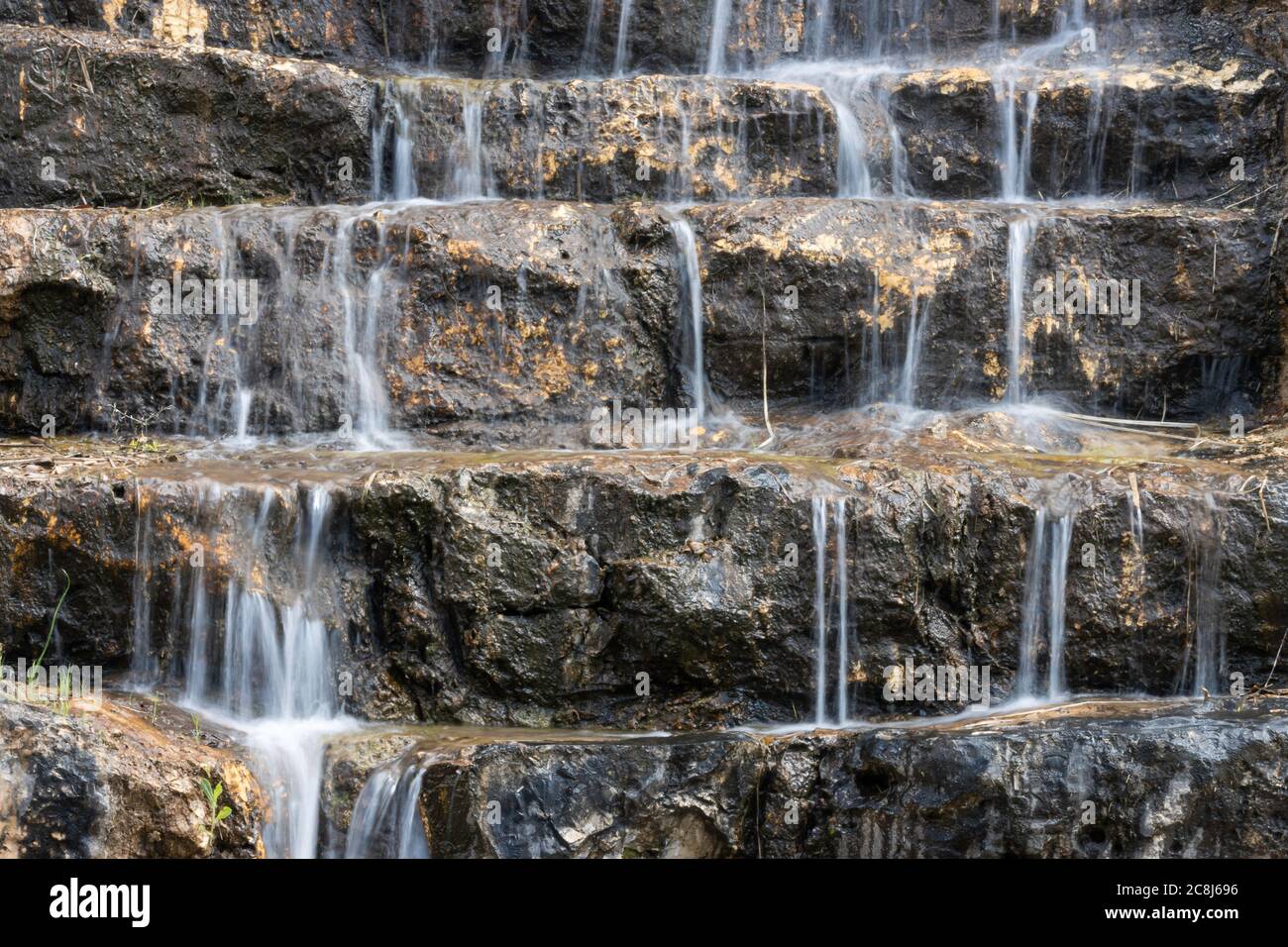 Wasser fällt in mehreren kleinen Kaskaden über Felsstufen, in einer langen Belichtungsaufnahme. Stockfoto
