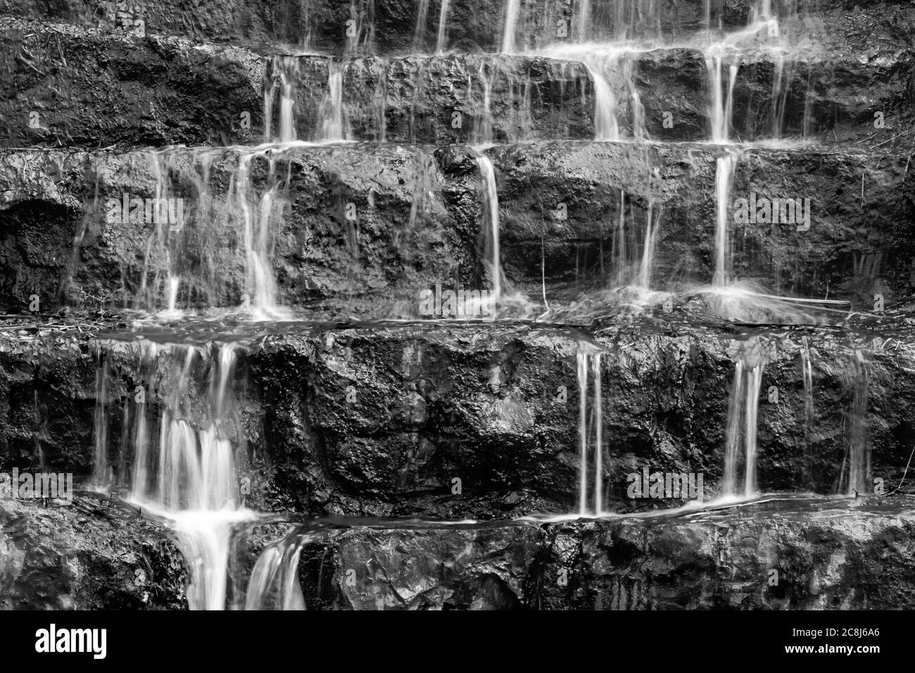 Wasser fällt in mehreren kleinen Kaskaden über Felsstufen, in einer langen Belichtung schwarz-weiß-Foto. Stockfoto