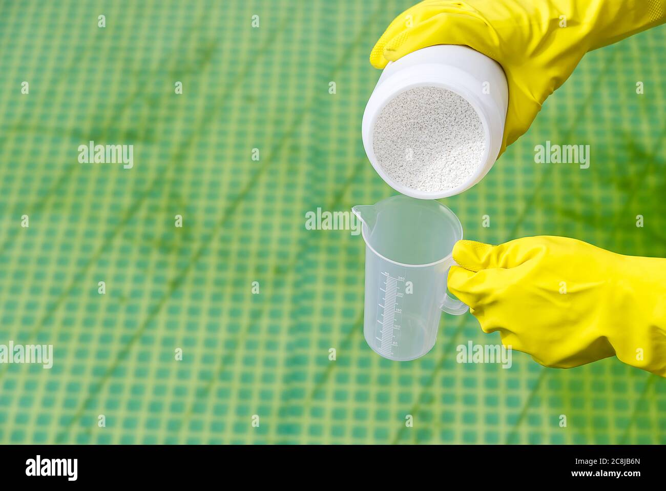 Zugabe von Chlorpulver für den Pool, um Algen zu entfernen und Wasser zu desinfizieren. Aufblasbares Schwimmbad Pflegekonzept. Stockfoto