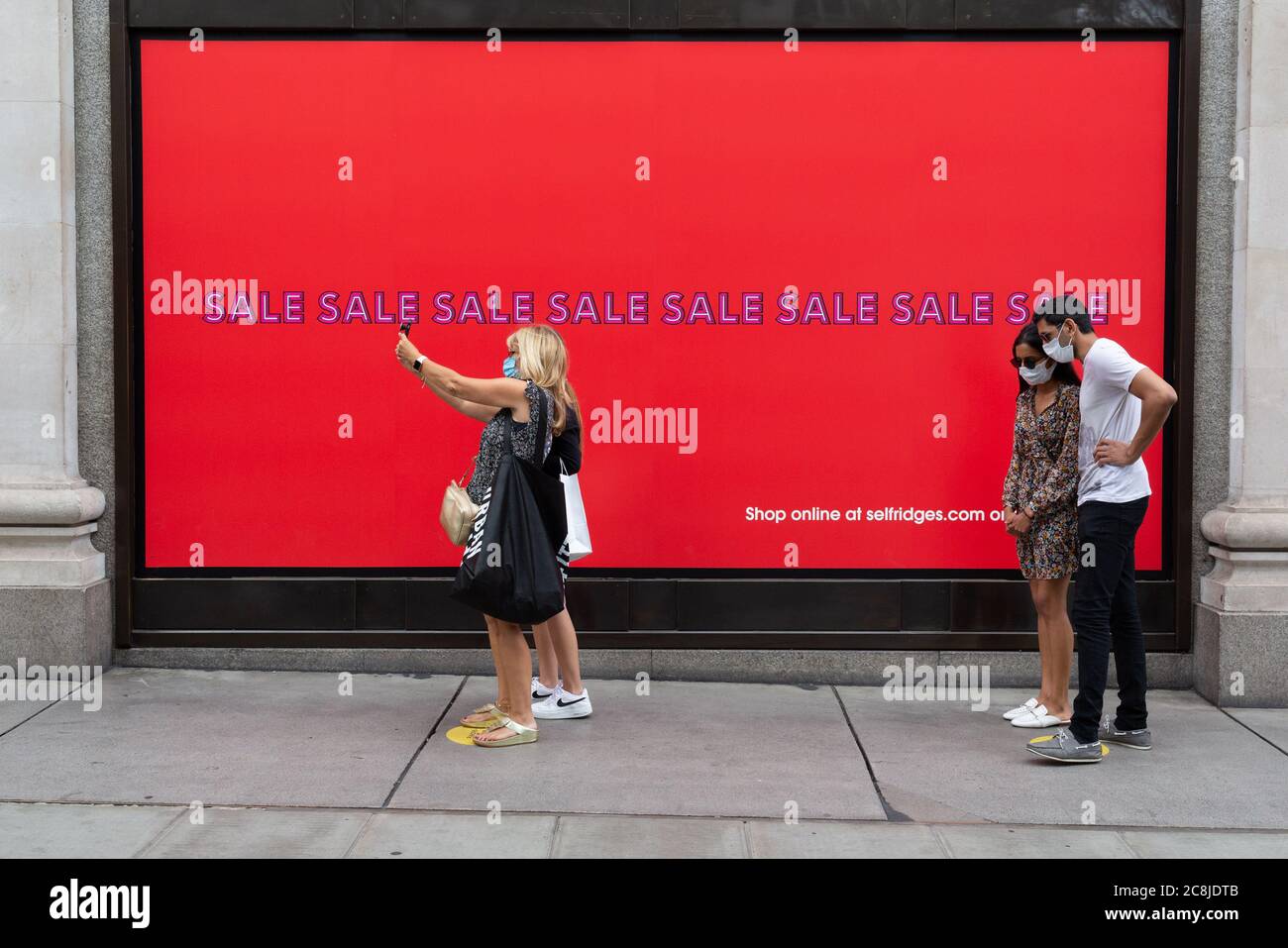 An dem Tag, an dem die Pandemierichtlinien für Käufer in England das Tragen von Gesichtsbezügen in Geschäften zwingend erforderlich machen, laufen die Käufer am 24. Juli 2020 in London, England, an den Verkaufsfenstern von Seflridges in der Oxford Street im West End der Hauptstadt vorbei. Stockfoto