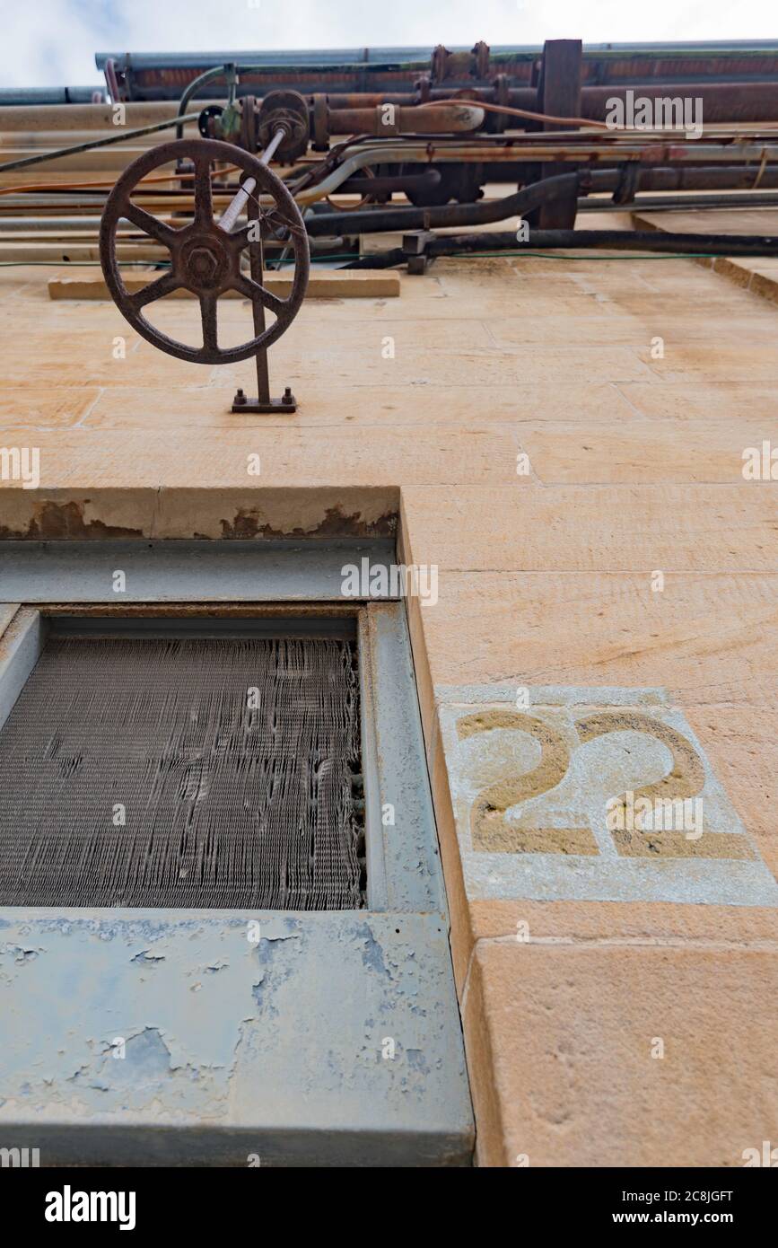 Blick auf ein Rad über einem Fenster vor einem der ehemaligen Werkstätten auf Cockatoo Island im Sydney Harbour, New South Wales, Australien Stockfoto